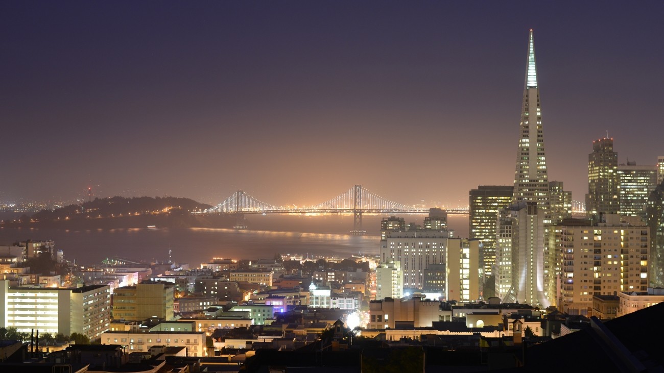 A nighttime view of the Bay including the Bay Bridge and Transamerica building 