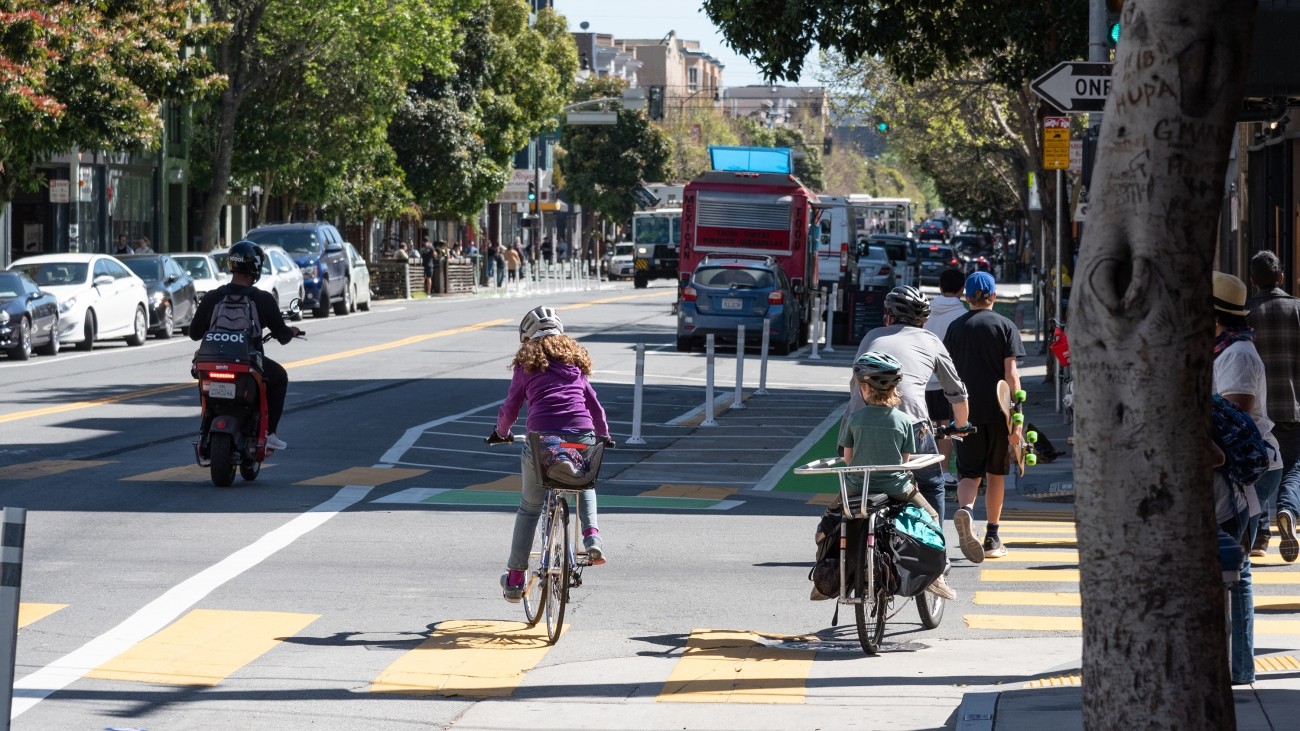 Kids and adults ride bikes in the bike lane on Valencia Street