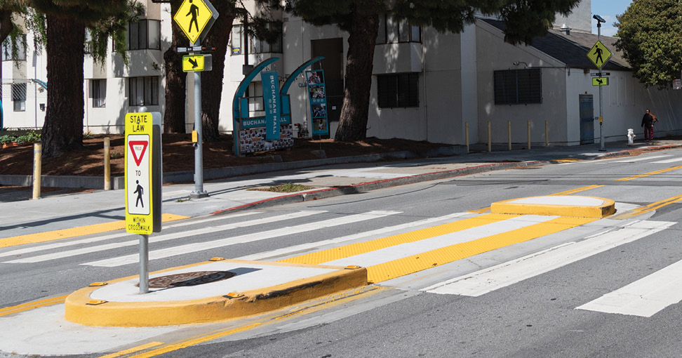 A raised concrete island in the middle of a crosswalk