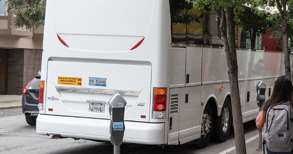 A section of curb is painted white, and a private shuttle bus is waiting at the curb.