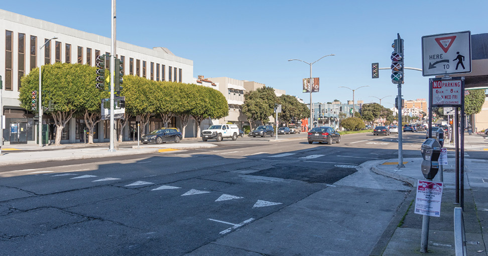 A series of triangles painted on the ground in front of a crosswalk