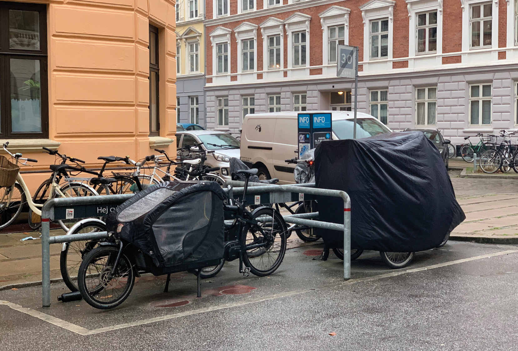 A view from the inside of a metal storage container with boxes stacked inside and a ramp leading to the exterior parking lot. A cargo tricycle is visible across the parking lot.