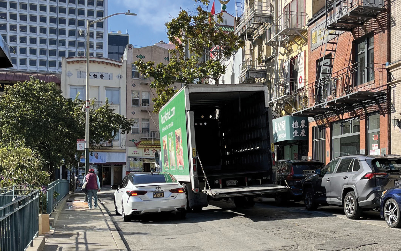 A double parked truck unloading on a crowded street.