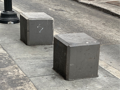 Two large concrete cubes on a sidewalk.