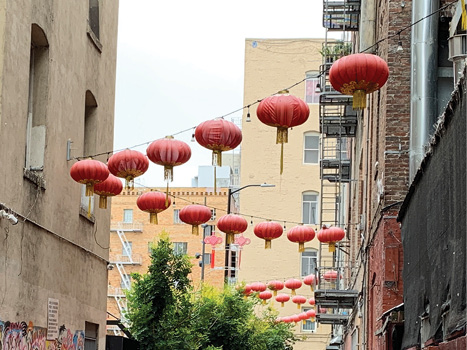 A view of red traditional Chinese lanterns strung diagonally between two buildings.