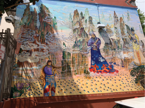 A large painting with three older men wearing colorful robes against a background of mountains and clouds.
