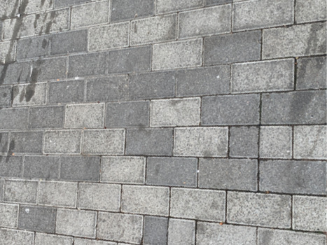 A close up of rectangular stone pavers, with a mix of dark grey and light grey pavers.