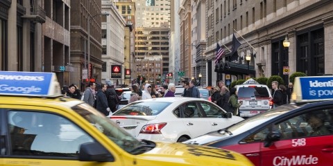 Taxis, an Uber, other cars, and people walking in congested downtown San Francisco