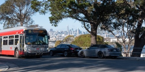 Muni bus drives past cityscape