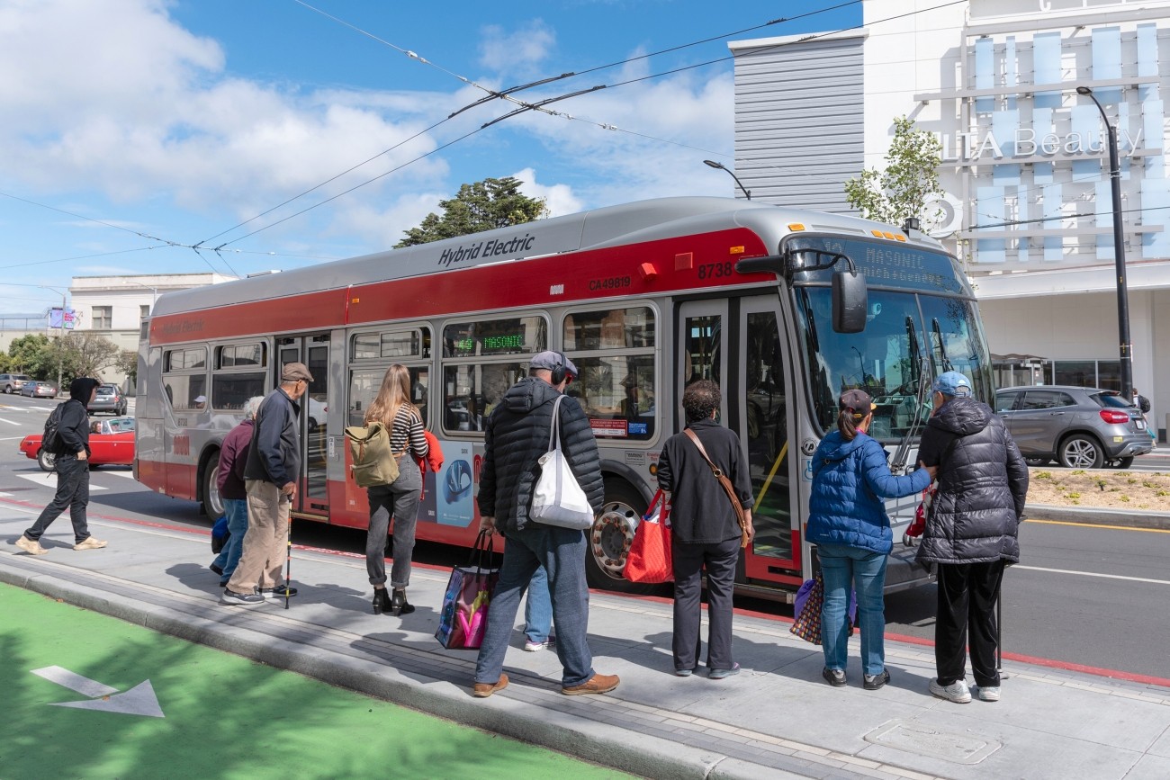 People boarding a bus from a bus boarding island adjacent to a bike lane