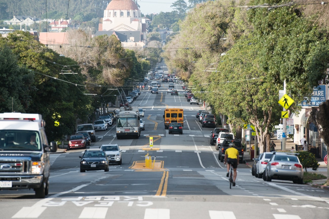 An image taken at Fulton and Arguello, looking down Arguello, with a car and a person biking