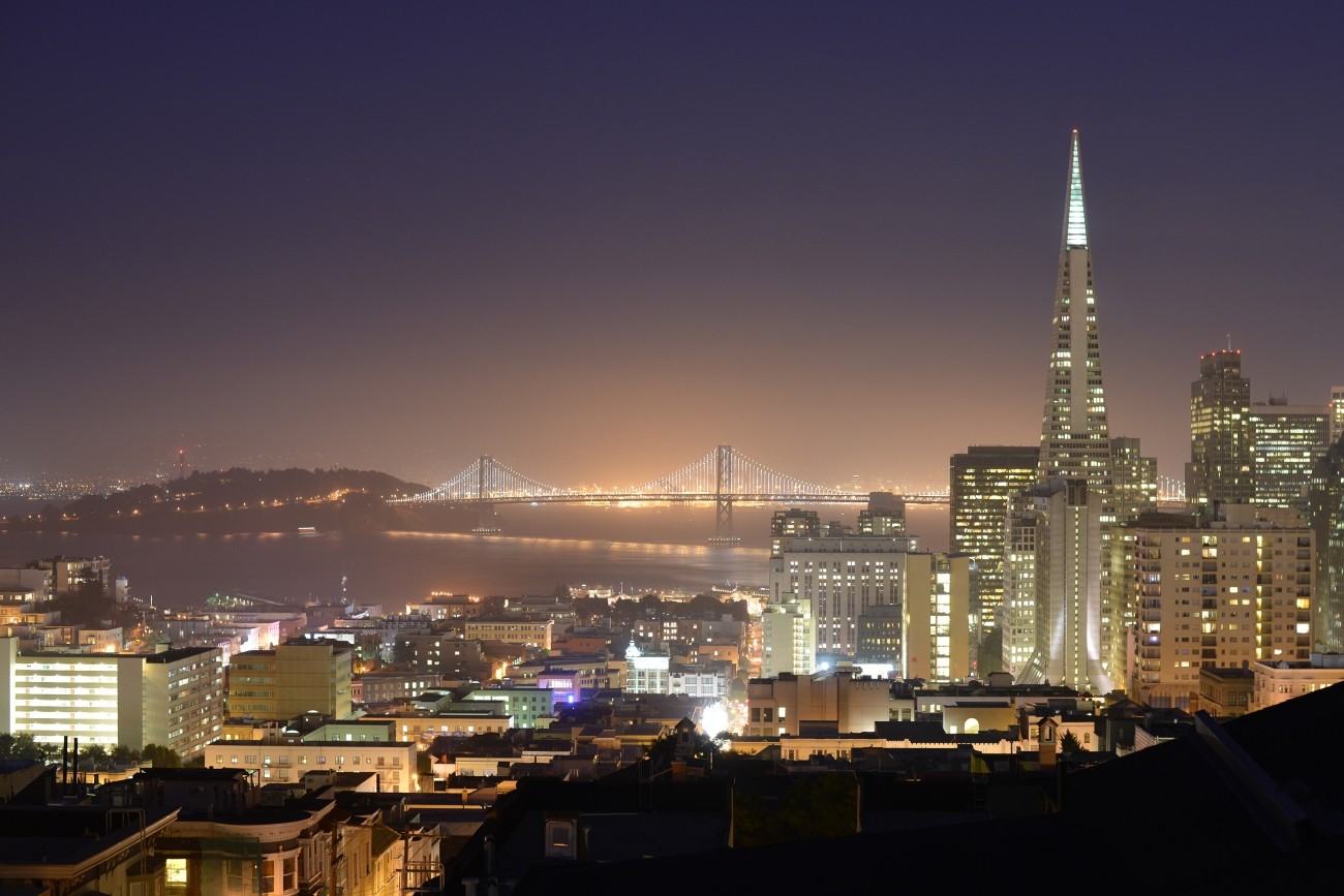 A nighttime view of the Bay including the Bay Bridge and Transamerica building 