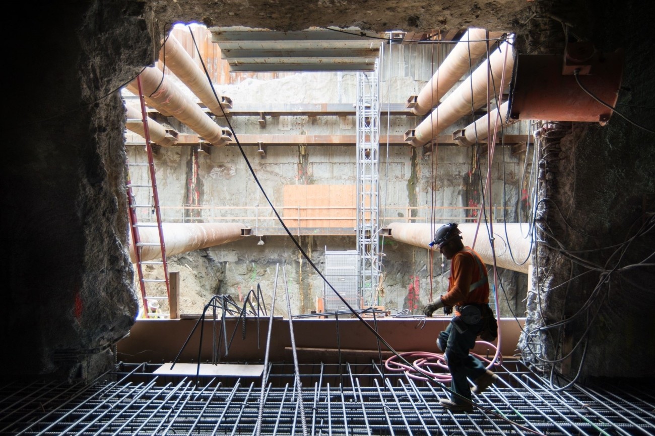 Backlit photo of a construction worker stepping across a rebar cage.