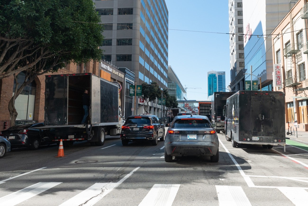 Commercial truck double parked in the downtown area. 