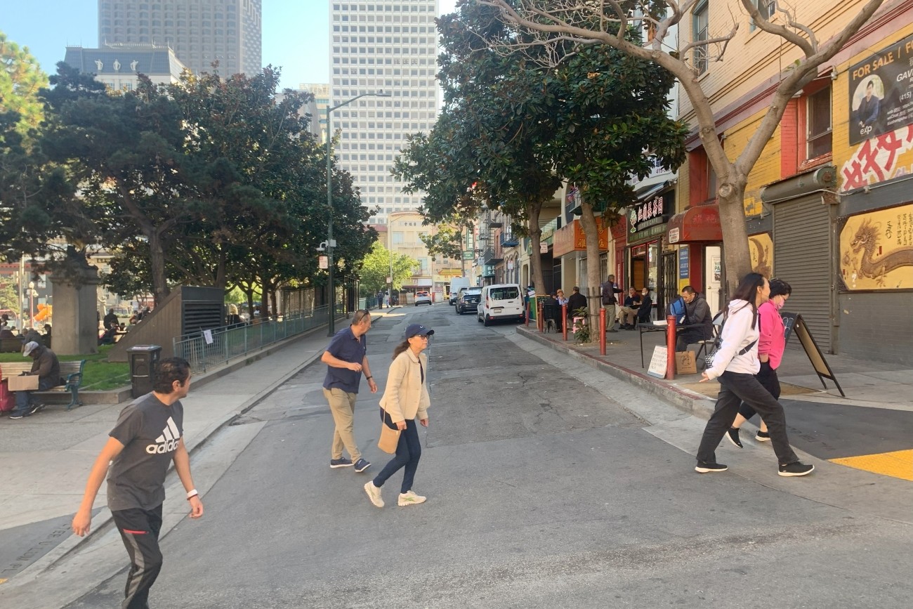 Pedestrians walking across Walter U Lum Place in San Francisco's Chinatown