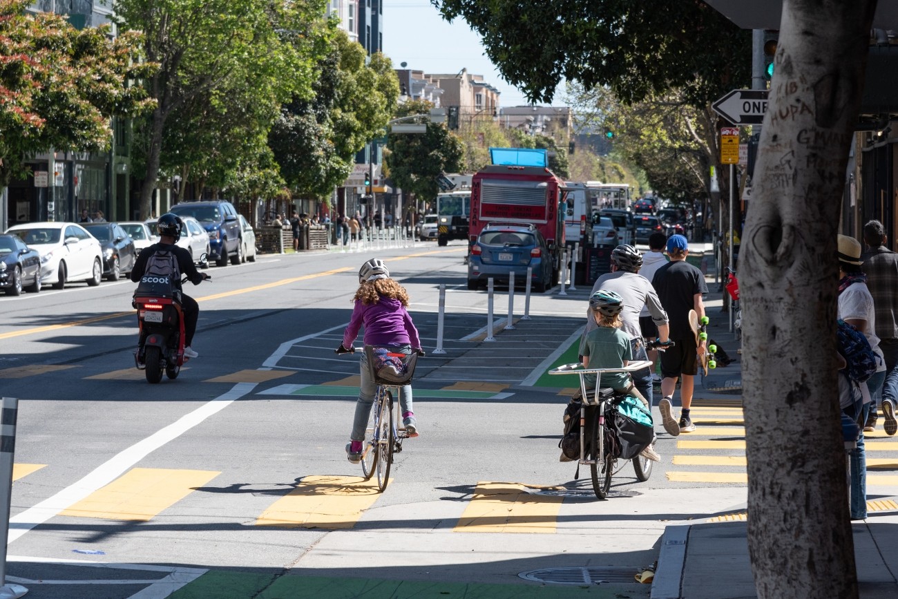 Kids and adults ride bikes in the bike lane on Valencia Street