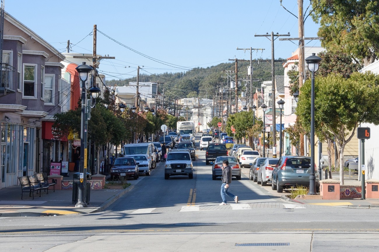 A person crosses Leland Ave in Visitacion Valley.