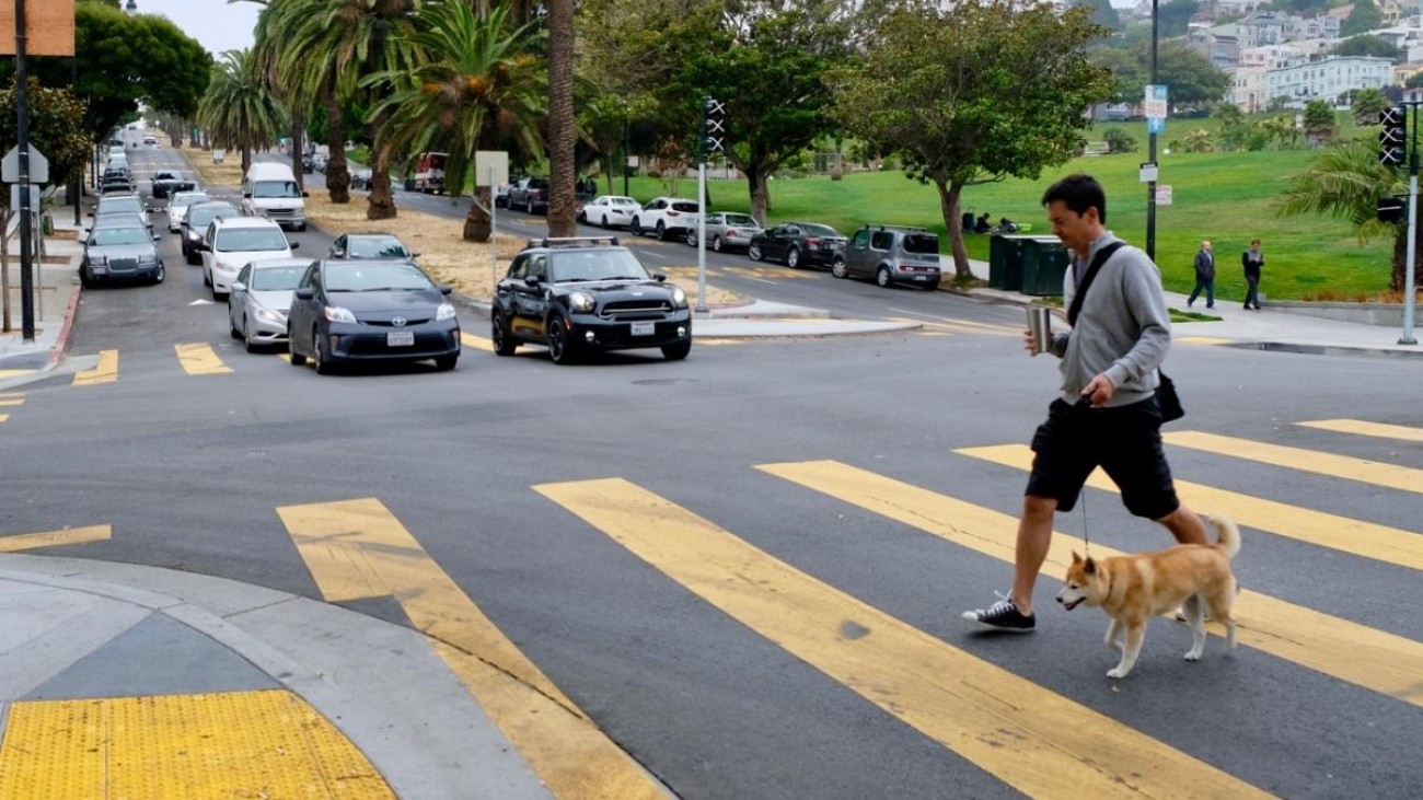 A pedestrian crossing a crosswalk near Dolores Park 