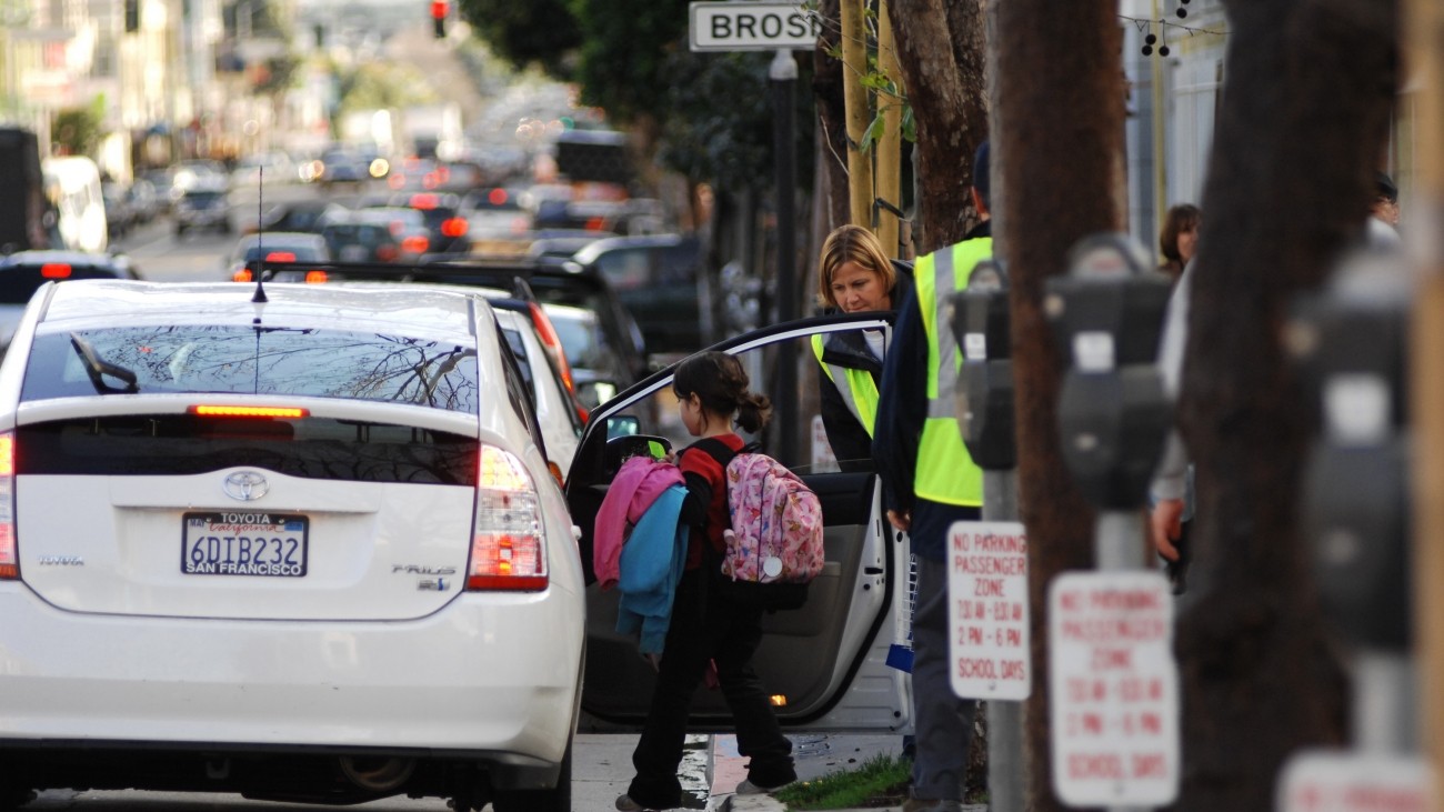 A child getting into a Prius with help from a school aide