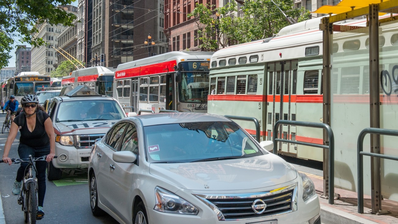 TNC vehicle on Market Street with transit and a bicyclist