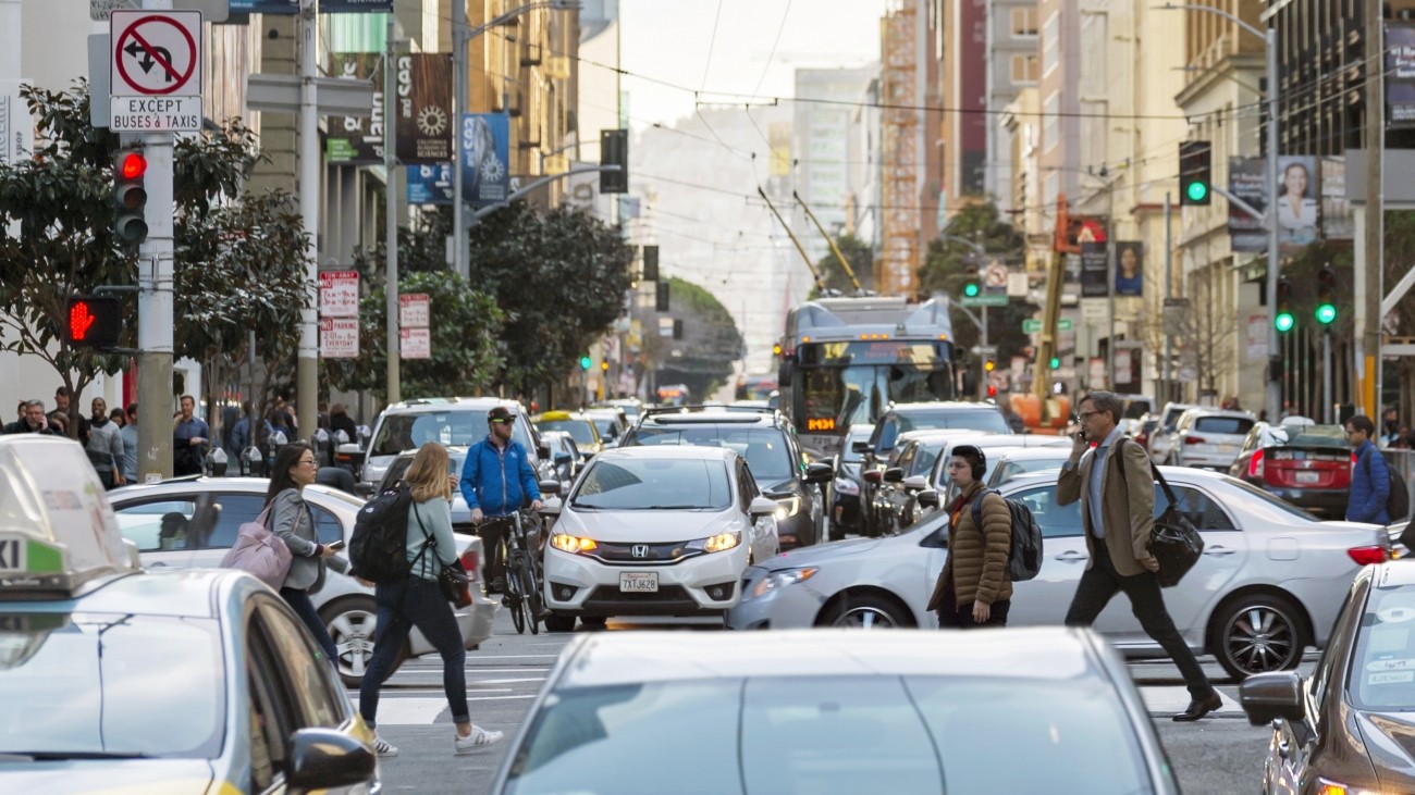 A congested road with cars, people walking, a bus, and a bike at Mission and 1st