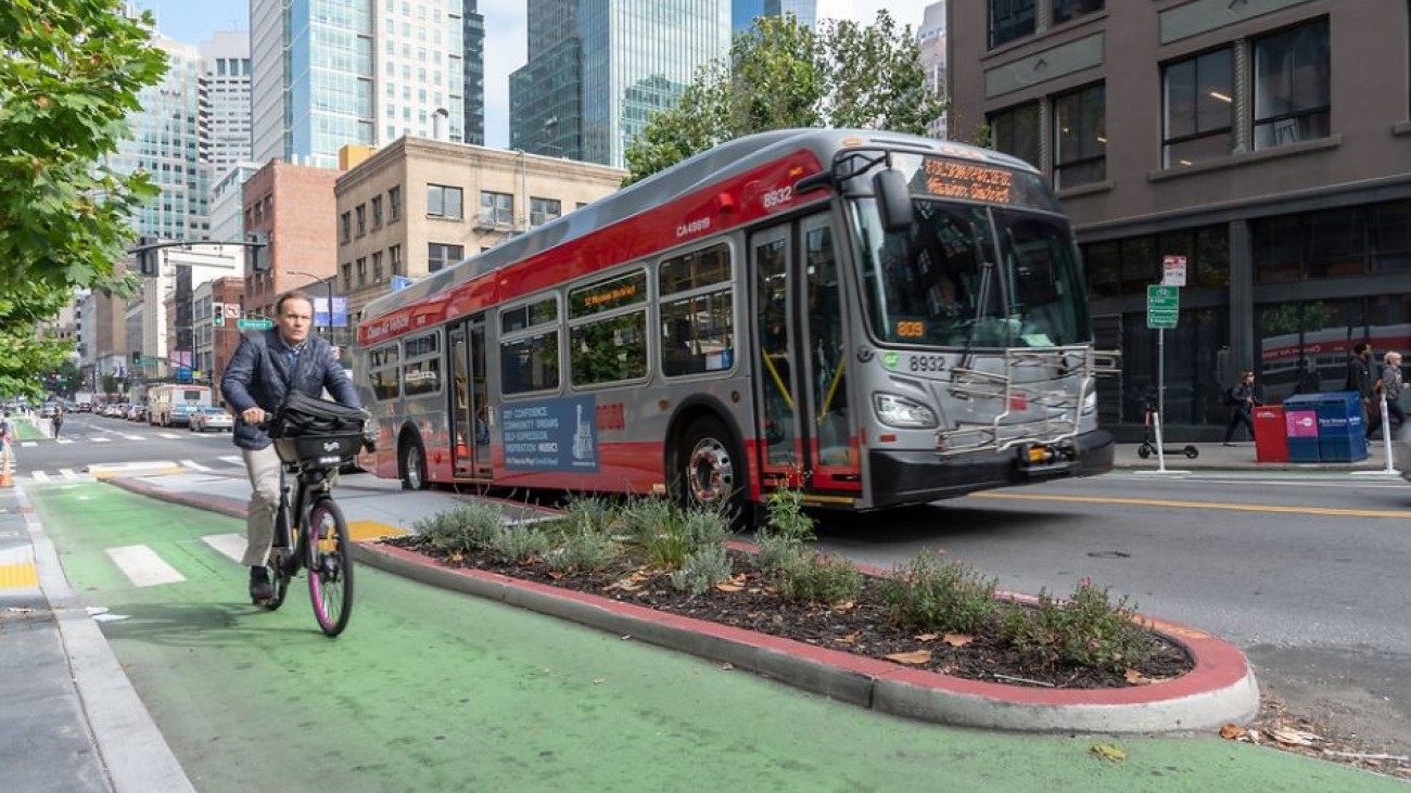 Man riding a bike next to a bus