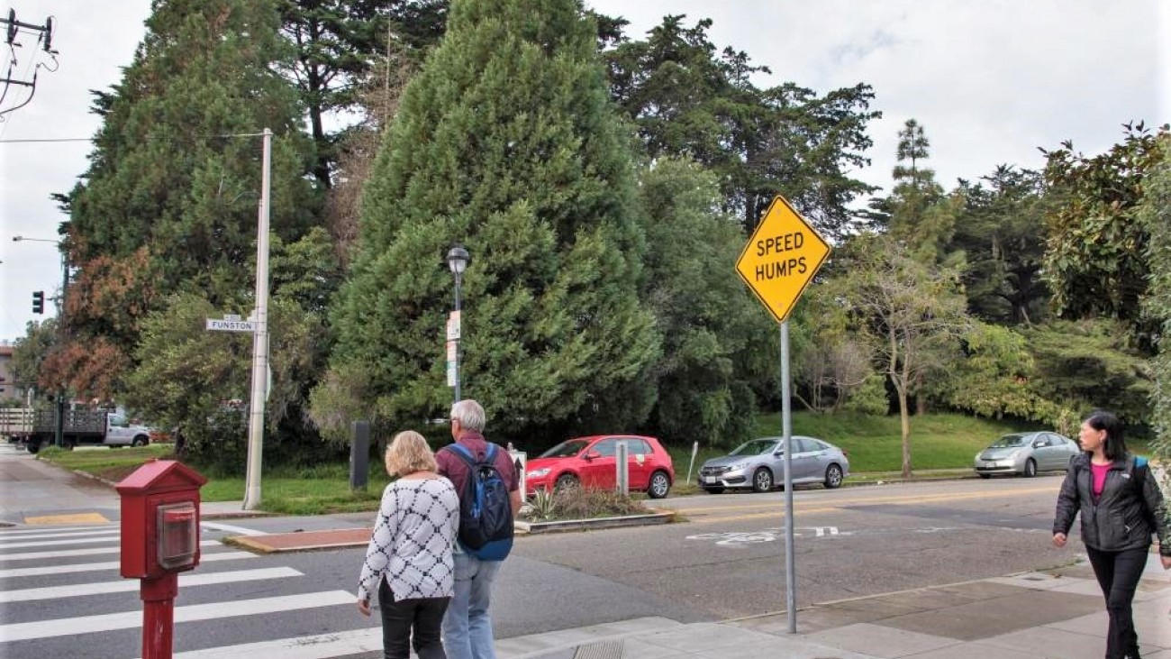 people walking across a street with speed bumps