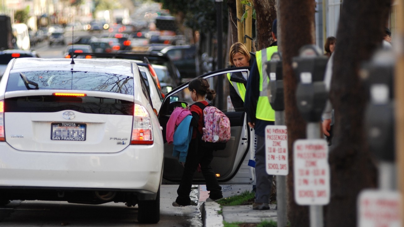 A child getting into a Prius with help from a school aide