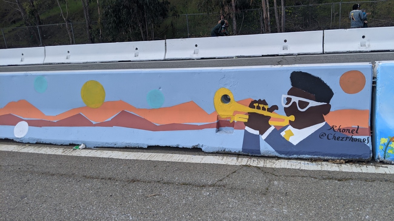 Mural of person playing trumpet in a blue suit and white glasses
