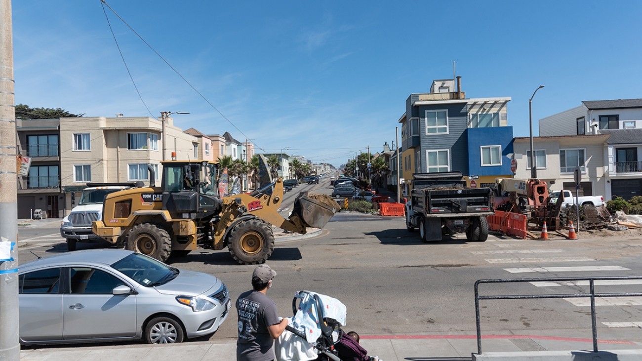 Person with stroller observing construction on Taraval Street