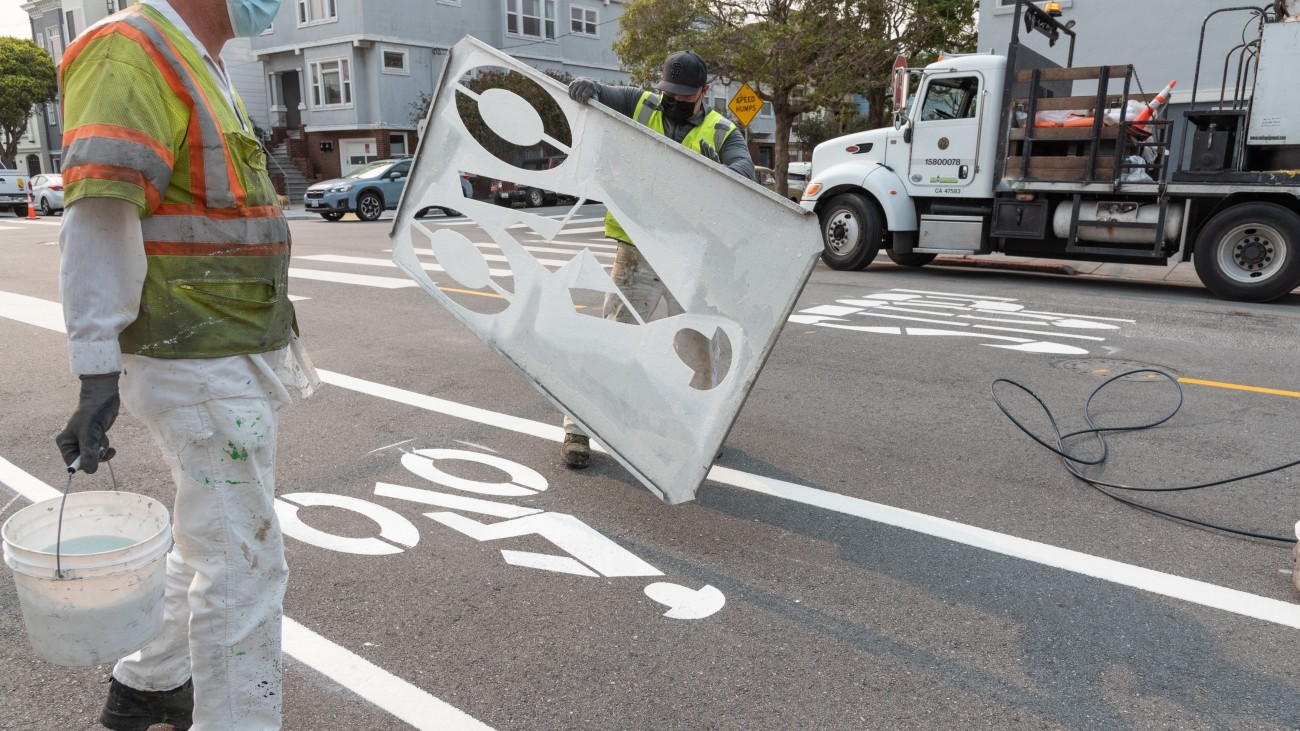 SFMTA staff lifting bike lane stencil 