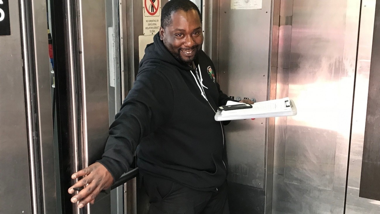 A BART attendant holding the elevator door open.