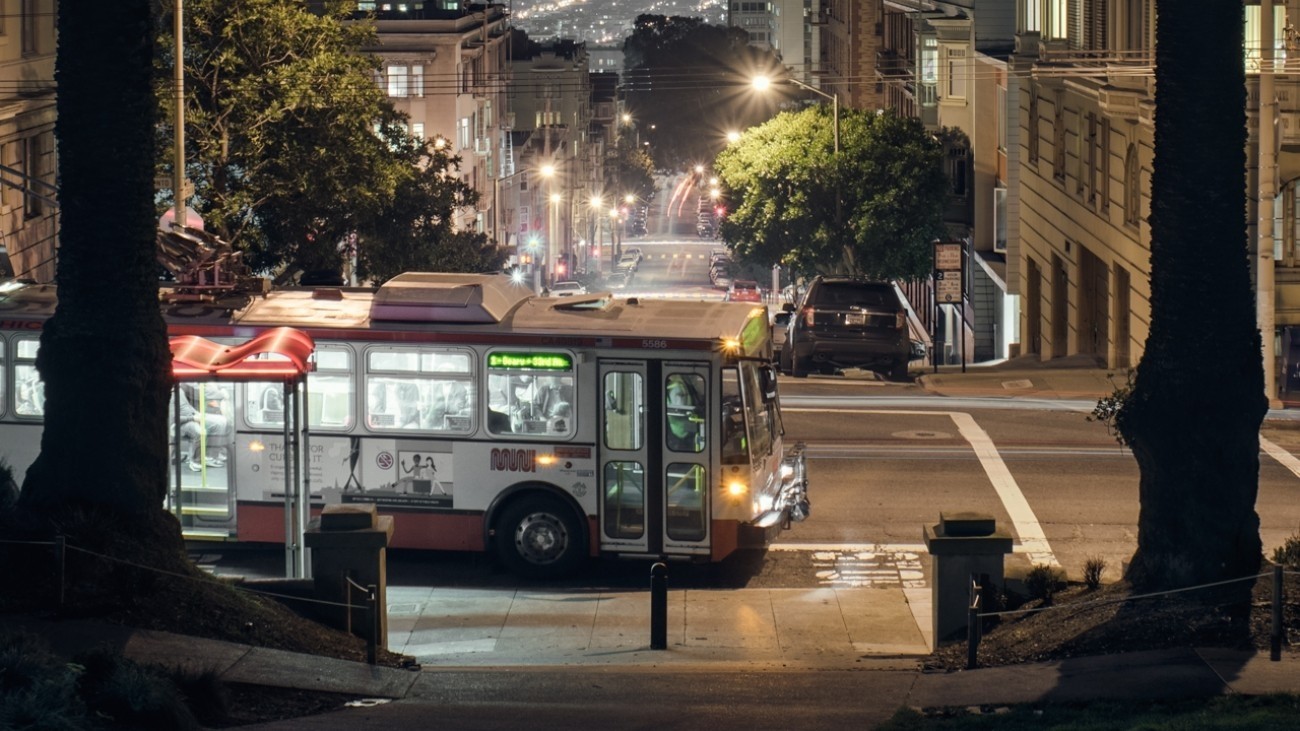 A bus driving across the street at night.
