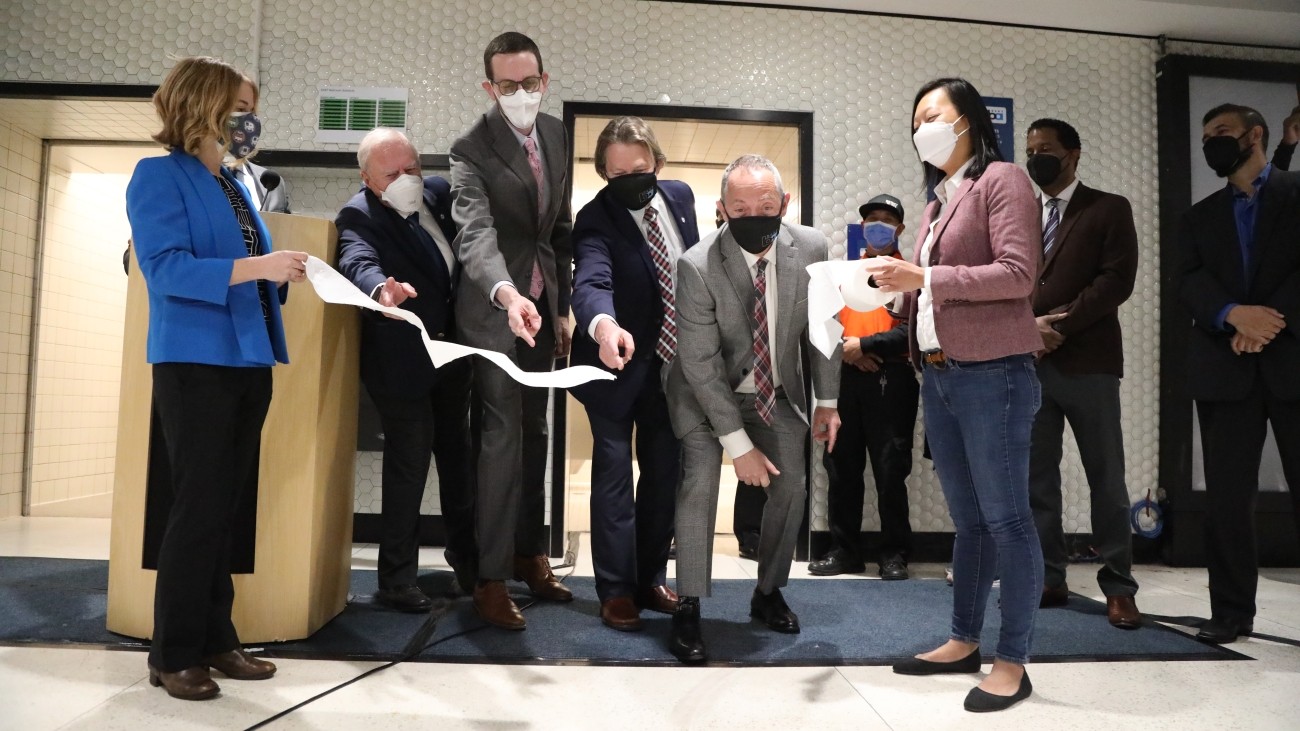 Agency and city officials gather outside of the new restrooms and cut the toilet paper for the toilet paper-cutting ceremony.