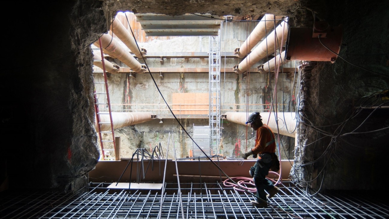 Backlit photo of a construction worker stepping across a rebar cage.