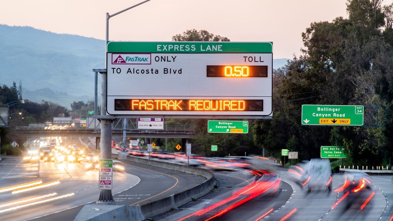 Express lane freeway signage with blurred vehicle lights on the road below it