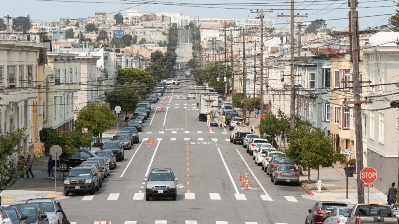 West-facing view of Anza Street at the intersections with 17th Ave. A work crew paints new bike lanes.