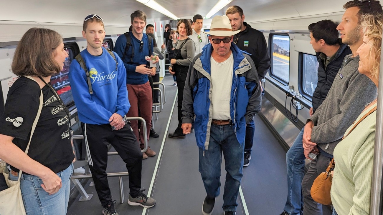 Interior of a new train, with members of the public touring the train. 
