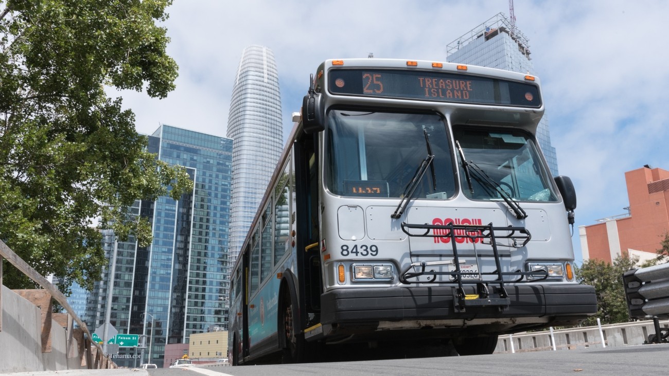The 25 Muni bus which serves Treasure Island on the road with Salesforce building and other buildings visible in background