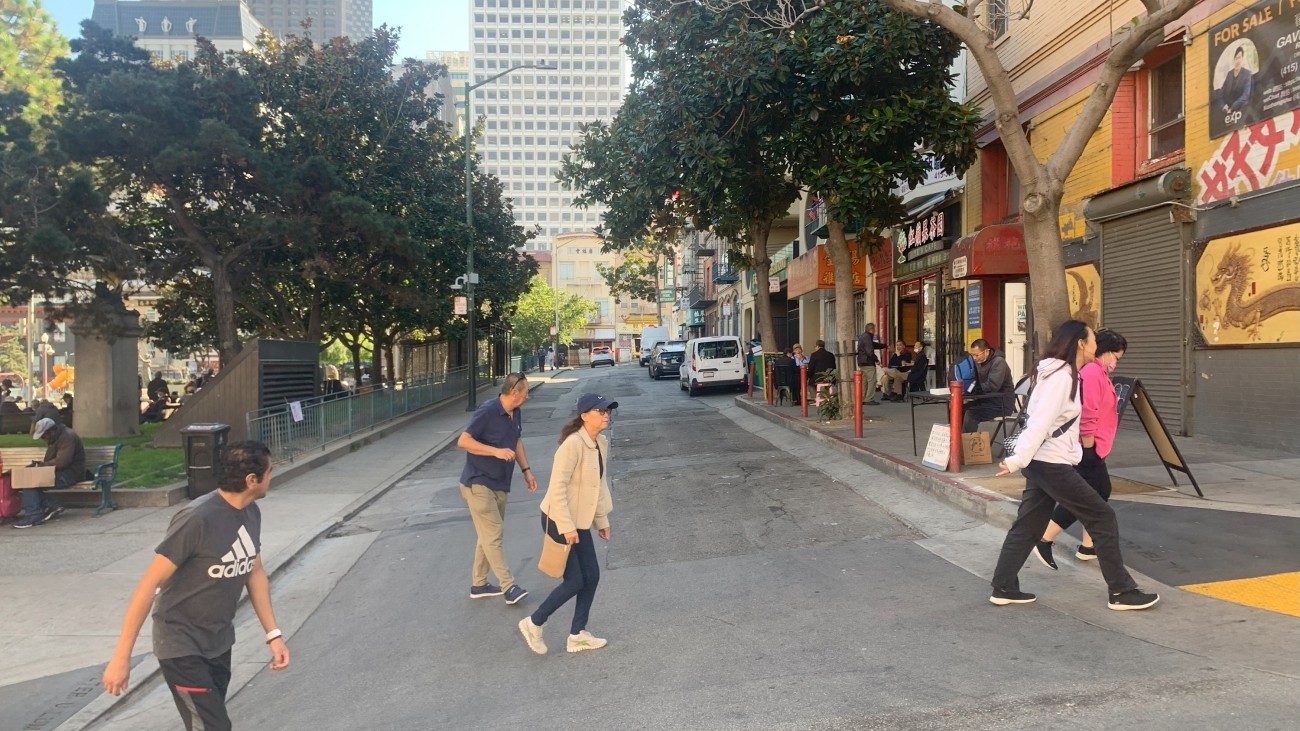 Pedestrians walking across Walter U Lum Place in San Francisco's Chinatown