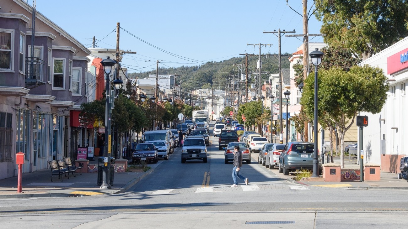 A person crosses Leland Ave in Visitacion Valley.