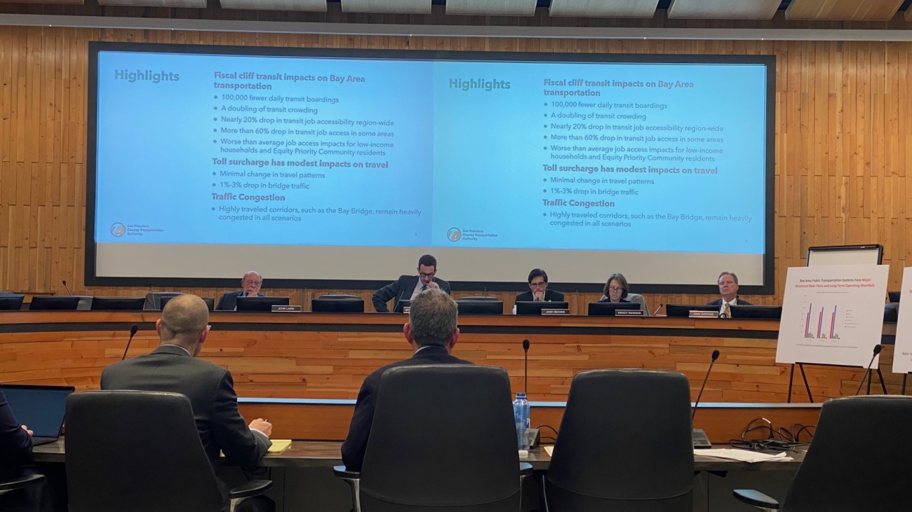 Government officials sitting in a board room with a presentation on screen