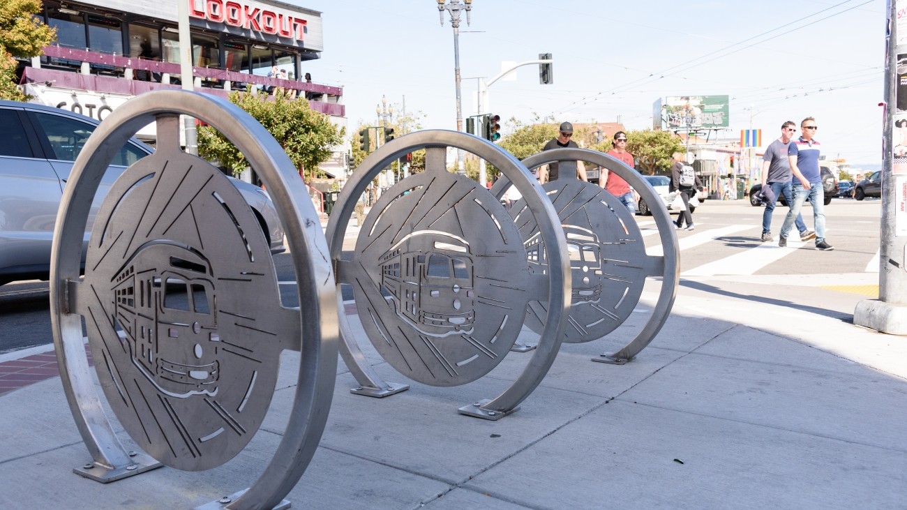 Silver, circular bike racks with decorative streetcar designs in the center of the bike rack