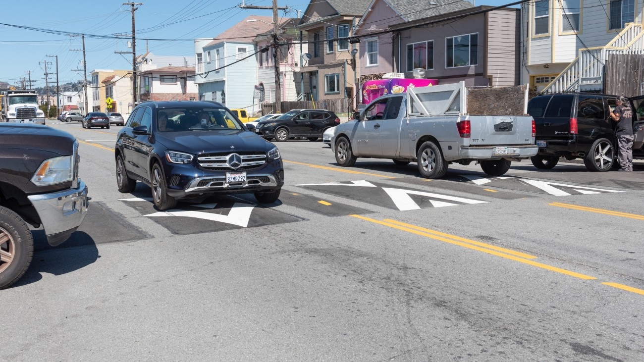 A black vehicle driving over a speed cushion