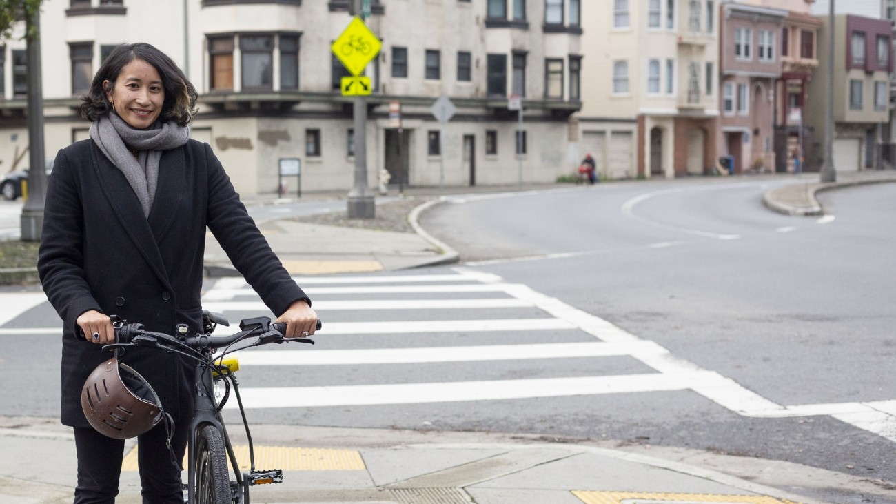 A woman with her bike on the sidewalk