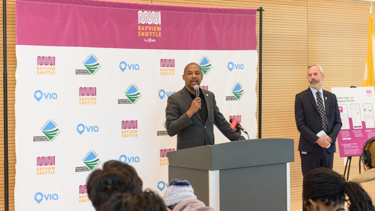 District 10 Supervisor Shamann Walton speaking at a podium with a microphone at the Bayview Shuttle launch event