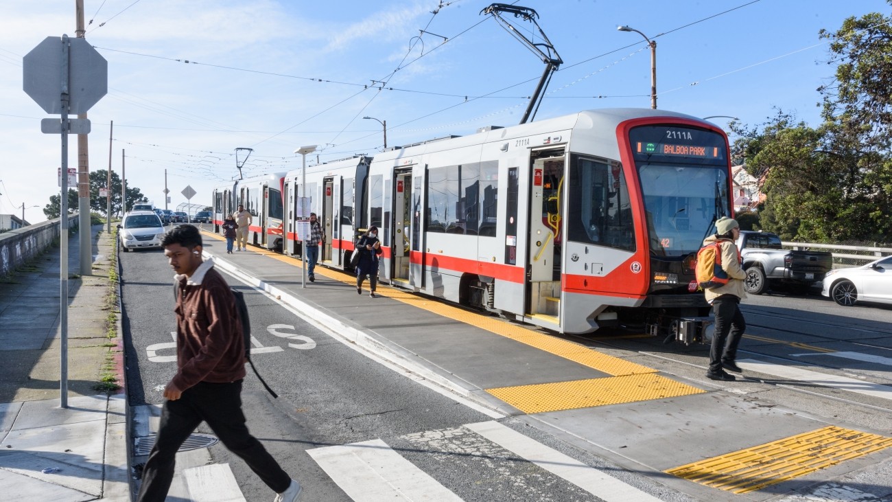Muni M at platform with pedestrians crossing