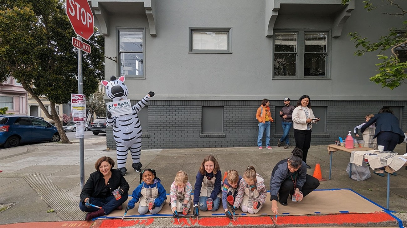SFCTA Chair Melgar pictured with students and SFMTA staff painting a curb red to daylight it
