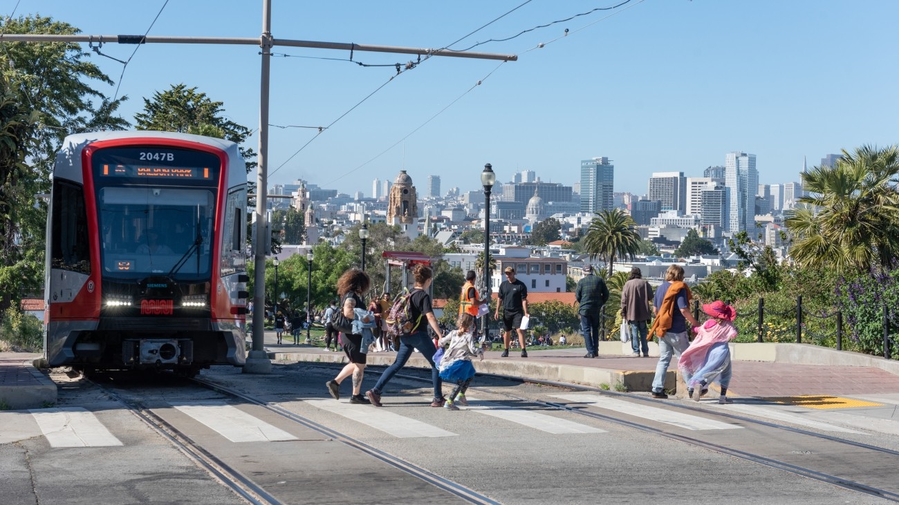 People Crossing in Front of J Church Train at Dolores Park