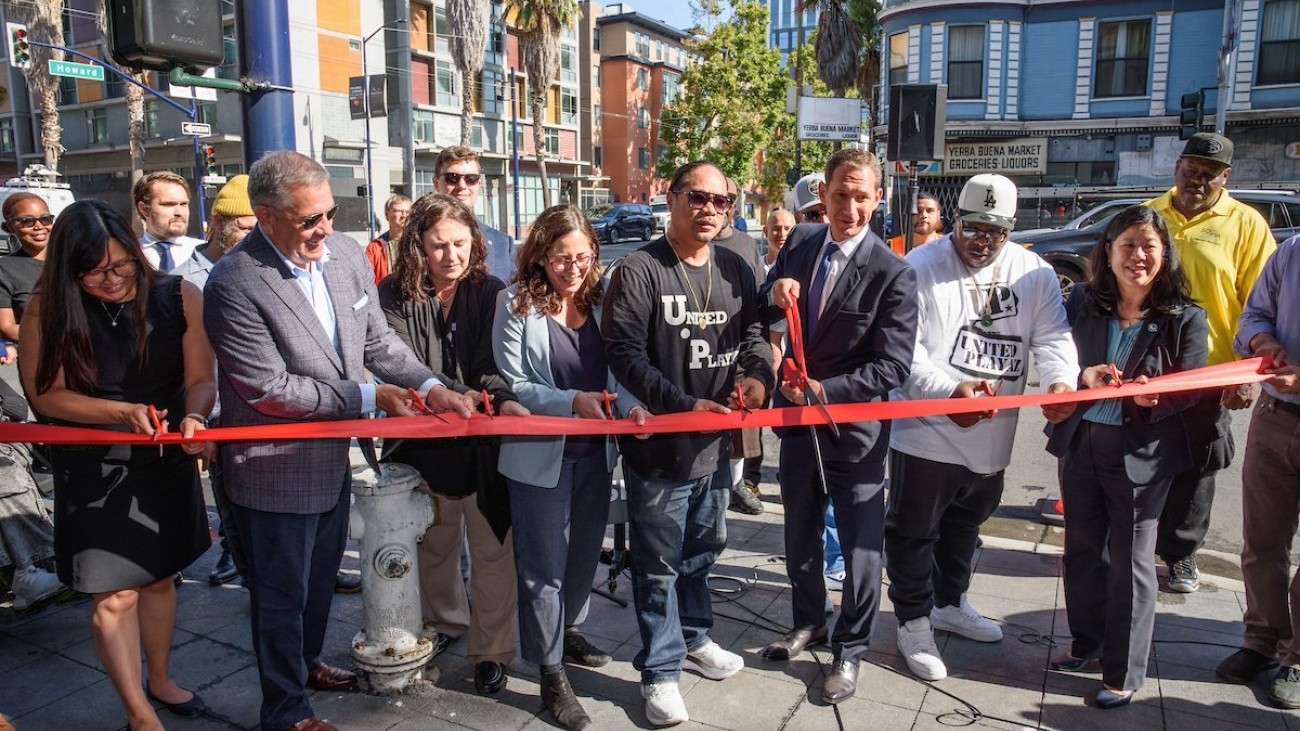 City officials, transportation officials, and community leaders cutting a red ribbon